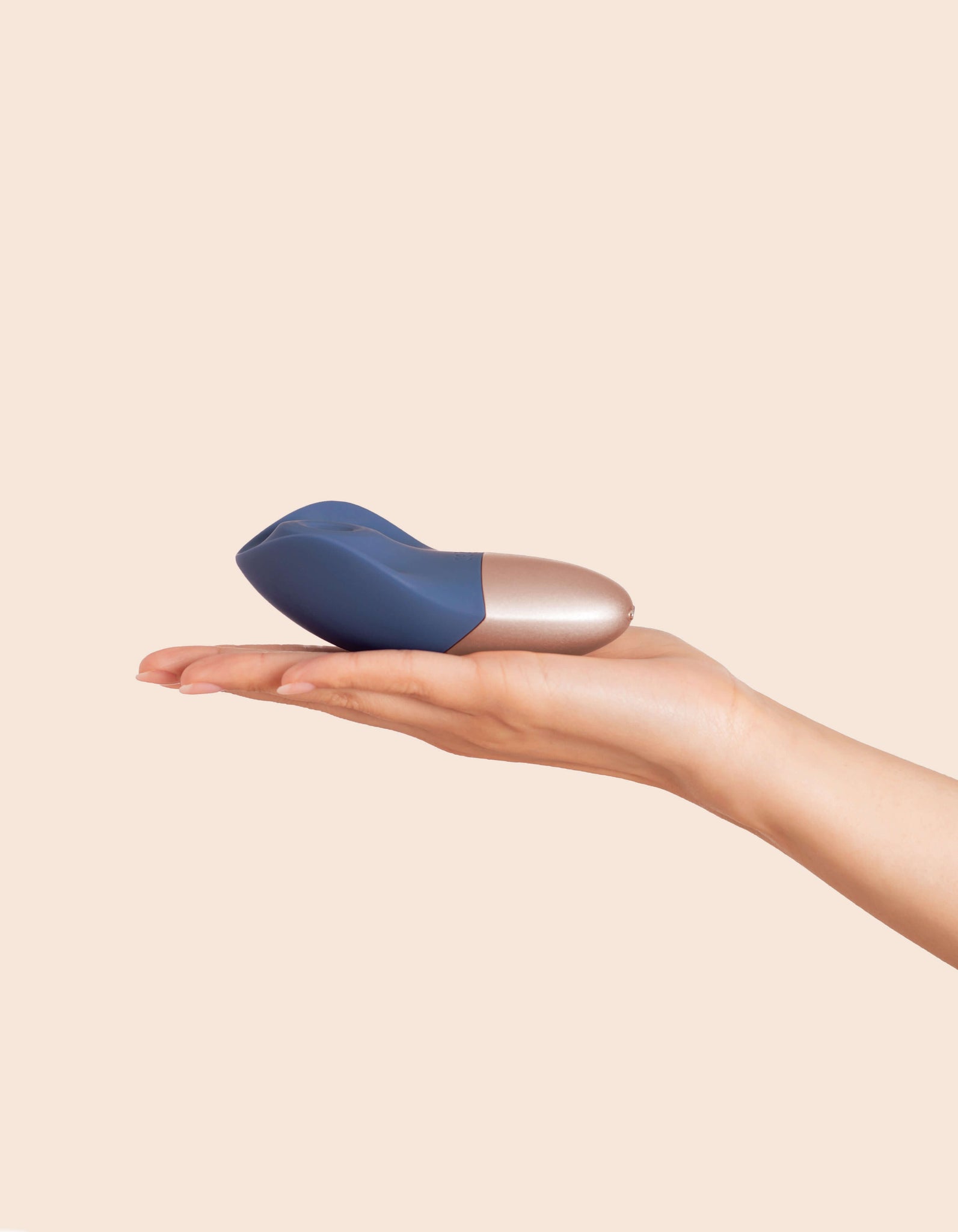 Deia's AROUSER clitoral stimulator-being held in hand indicating size